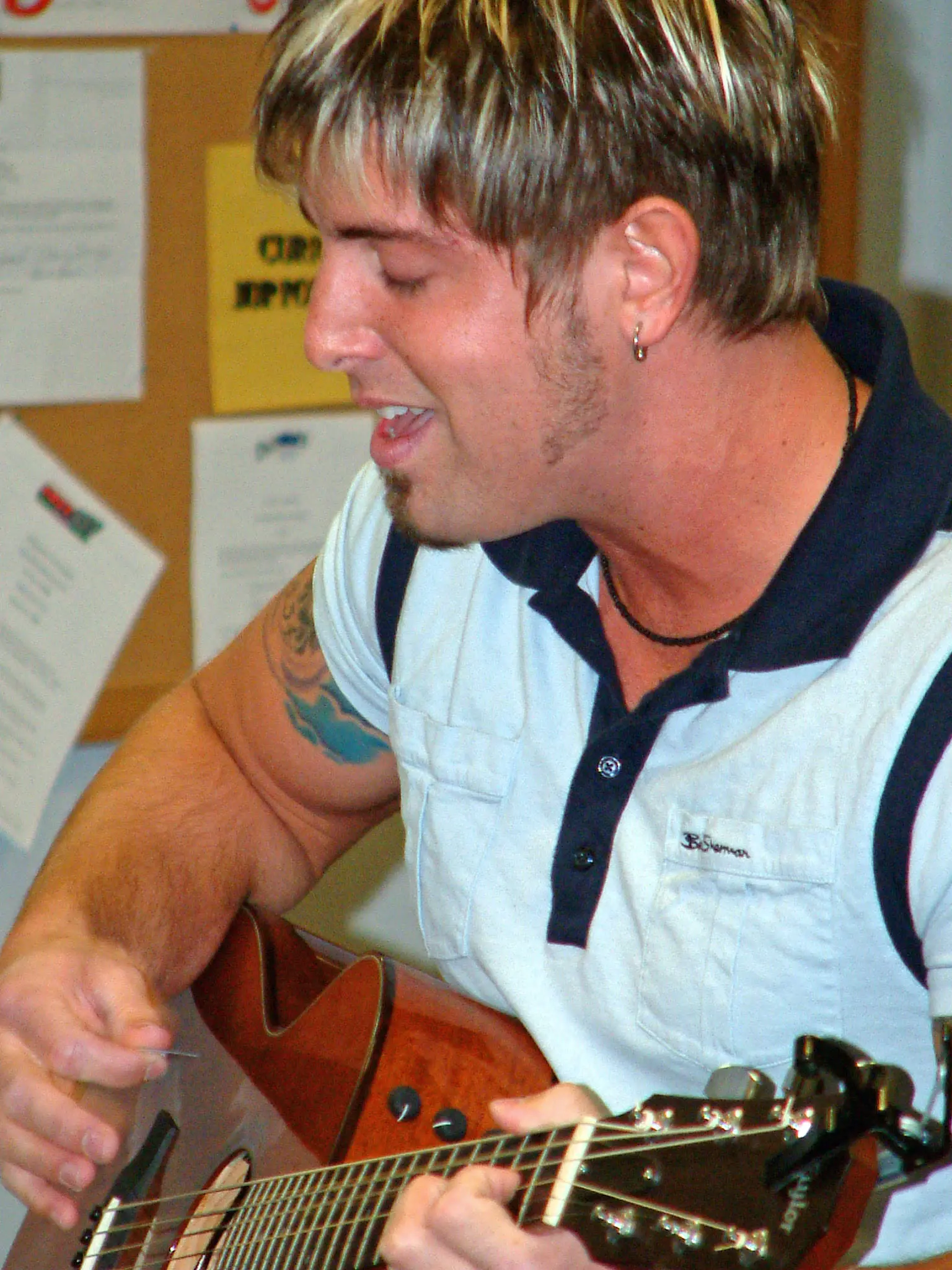 A musician singing while playing an acoustic guitar at a station appearance