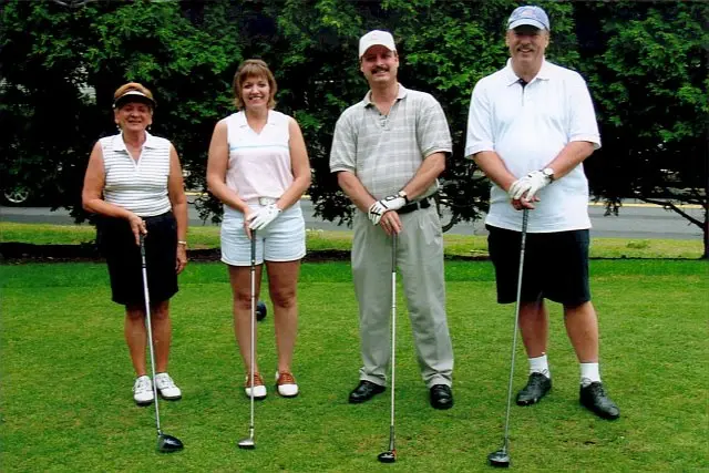 Three golfers leaning on their clubs on the fairway at a charity golf tournament