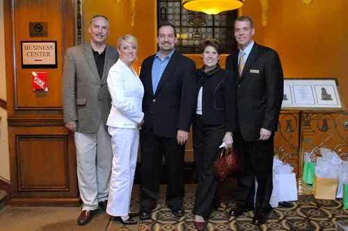 Six people in business dress posed together outside a hotel business centre