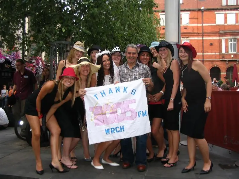 A group at an outdoor event holding a hand-lettered banner reading THANKS 100.5 FM WRCH