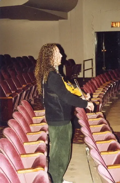 Rows of empty pink theatre seats before a show, one person walking down the aisle