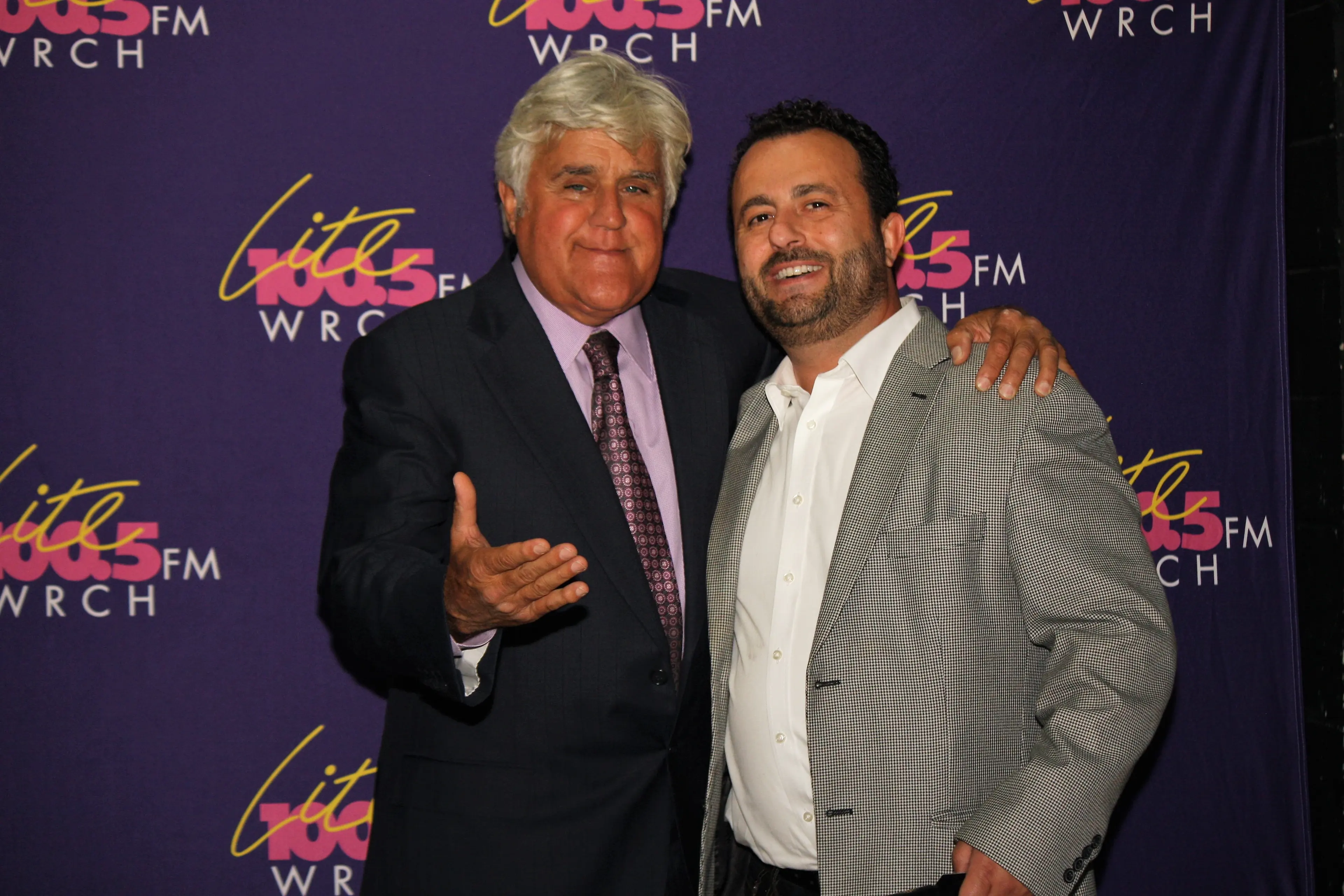 Two men photographed together on the red carpet in front of a Lite 100.5 FM WRCH backdrop