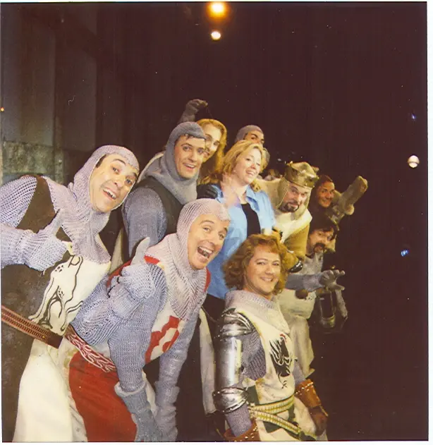 Another frame of the musical's cast in knight costumes, laughing together on stage