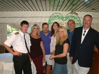 A group posed with a ship's officer in white uniform at a shipboard function