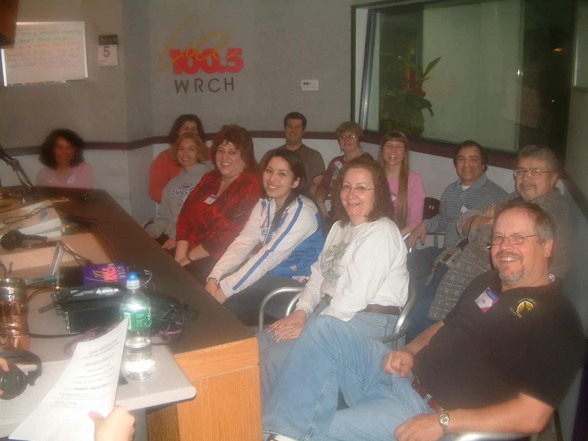 A group of listeners seated together in the WRCH studio beneath the Lite 100.5 logo