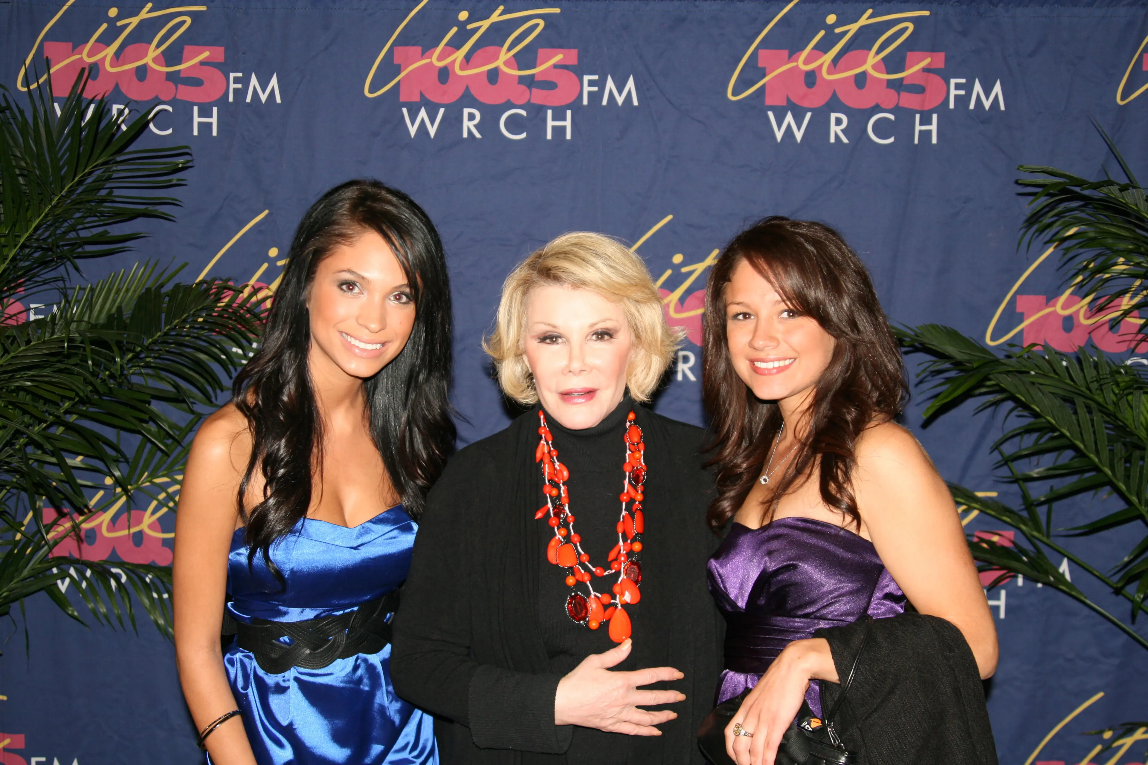 Three guests in evening dress posed together in front of a Lite 100.5 FM WRCH backdrop