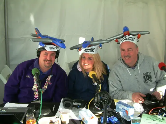 Three presenters at a remote broadcast desk wearing novelty Southwest Airlines aeroplane hats