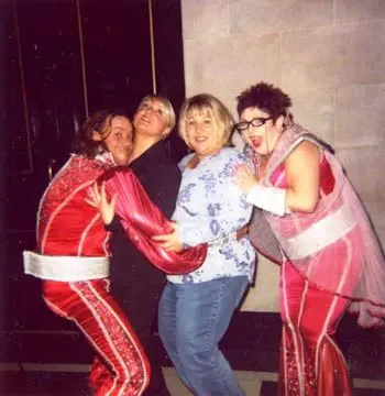 Four people in costume laughing and leaning on each other at a party