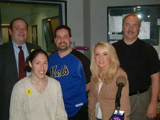 Four people posed together in the station lobby, one wearing a Mets jersey