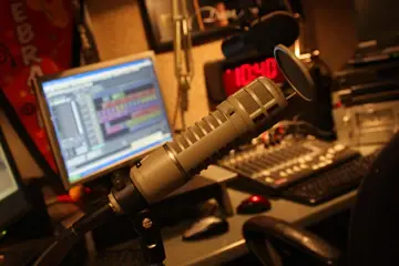 A studio microphone in front of a screen showing a multitrack audio edit in progress