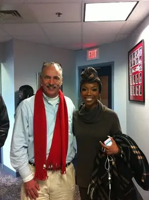 Allan Camp in a red scarf photographed with a guest in a station corridor